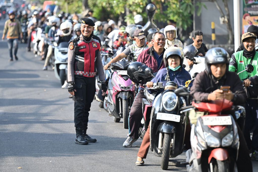 Anggota polisi berjaga di tengah antrean kendaraan yang akan mengisi bahan bakar minyak (BBM) di Denpasar, Bali, Selasa (13/10/2026). Pertamina Patra Niaga menambah pasokan BBM sebanyak 26.200 kiloliter secara bertahap untuk memenuhi kebutuhan di Bali menyusul antrean panjang kendaraan di sejumlah stasiun pengisian bahan bakar umum (SPBU) sejak Minggu (11/10). (ANTARA FOTO/Nyoman Hendra Wibowo)