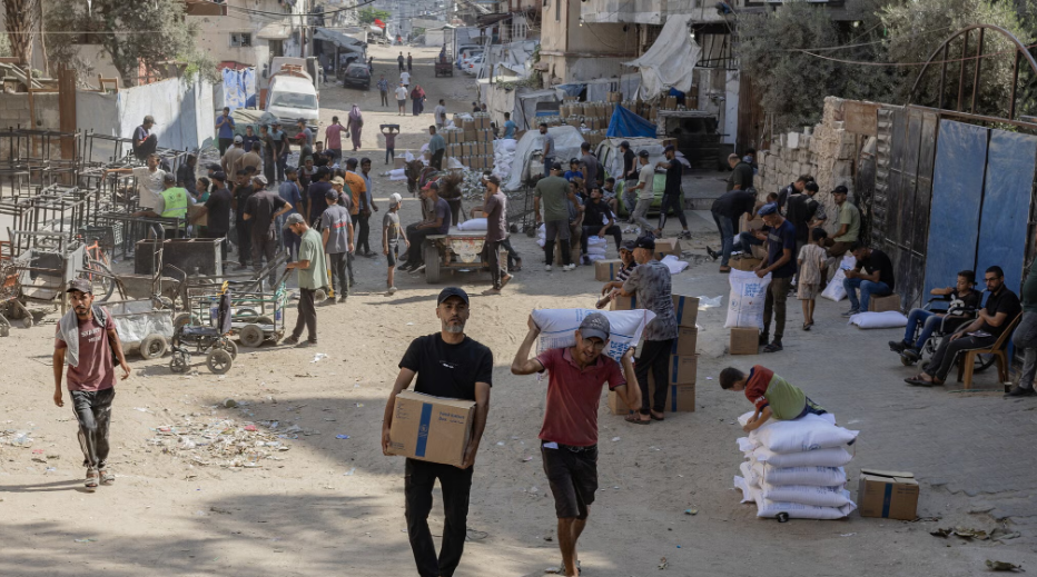 Palestinians carry food aid from a distribution point in Gaza last month.Credit...Saher Alghorra for The New York Times
