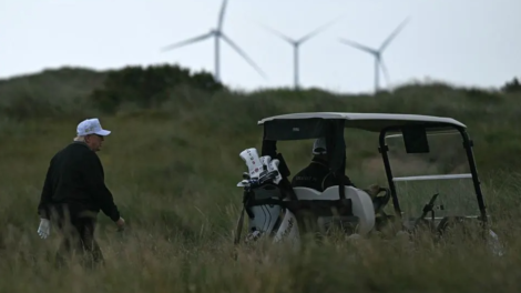 President Donald Trump backdropped by wind turbines while golfing at the Trump International Golf Links course in Scotland. AFP via Getty Images
