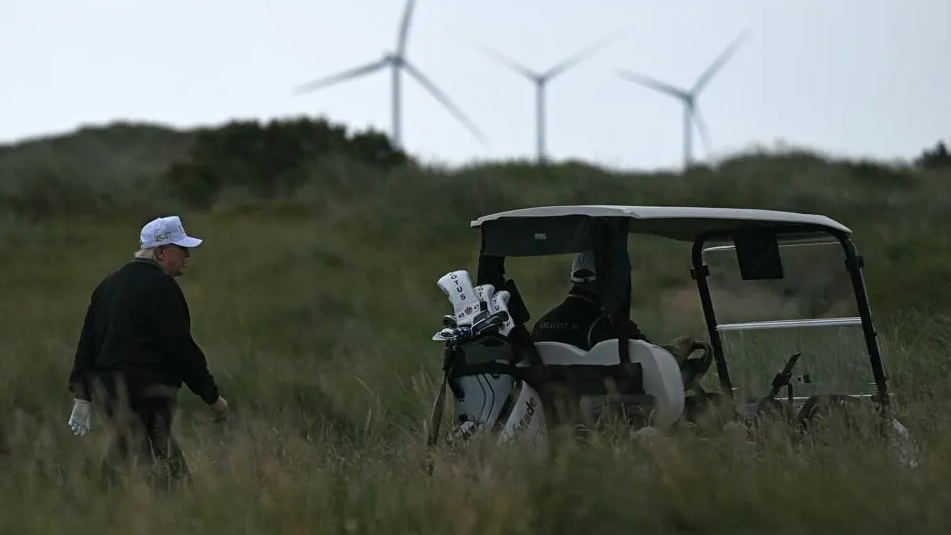 President Donald Trump backdropped by wind turbines while golfing at the Trump International Golf Links course in Scotland. AFP via Getty Images
