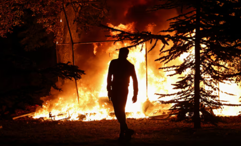 A person walks near flames as supporters of the electoral list "Student List - Students Win" celebrate following the first results of the parliamentary election in Belgrade, Serbia, October 25, 2026. REUTERS/Zorana Jevtic