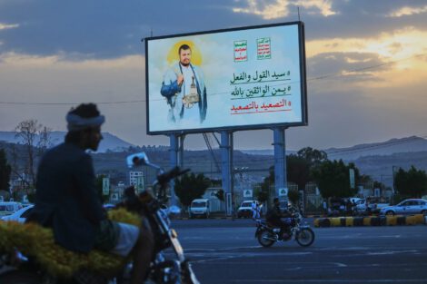 People ride their motorbikes under a billboard showing Houthi leader Abdul Malik al-Houthi with a phrase that reads in Arabic; “master of words and deeds” in Sanaa, Yemen, Monday, Sept. 21, 2026. (AP Photo/Osamah Abdulrahman)