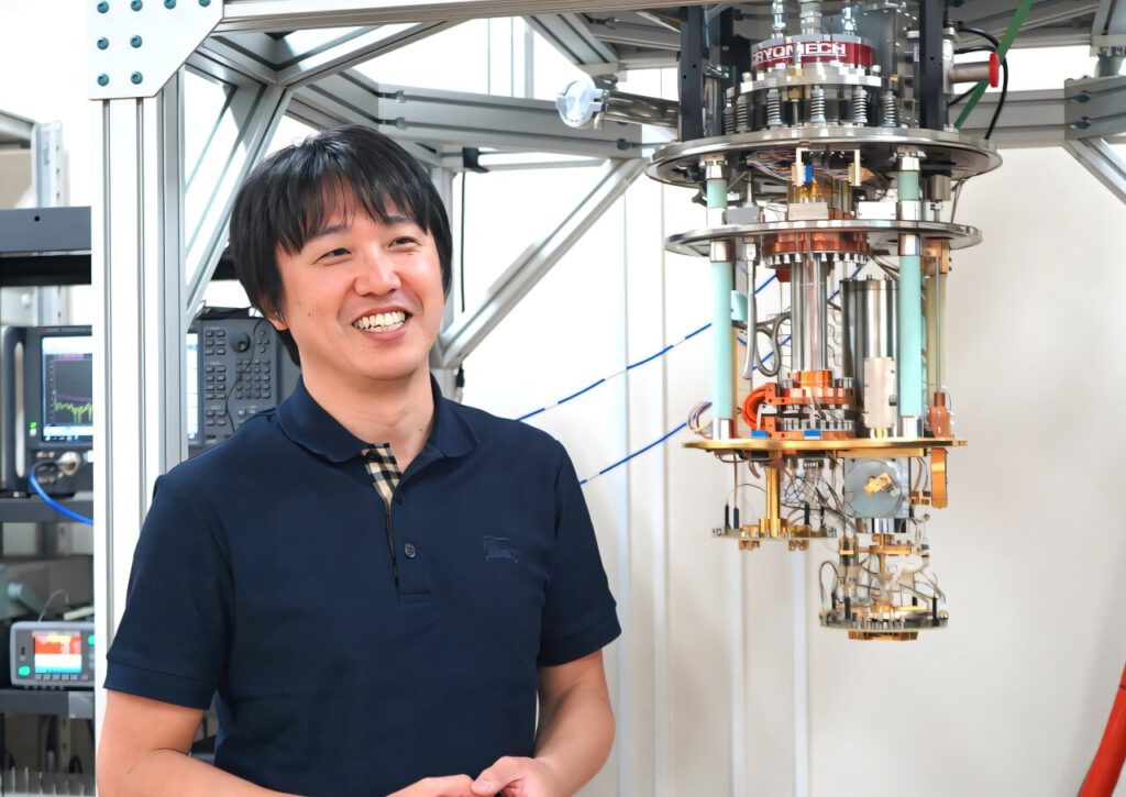 Miki describes the inside of the cryocooler used in quantum computers (photo taken at the Integrated Research Center of Kobe University, Port Island, Kobe). Credit: Kobe University