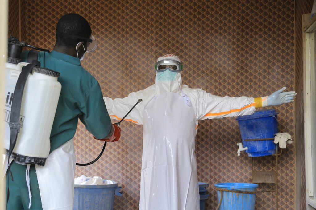 A healthcare worker in protective clothing is disinfected by a colleague inside a treatment center for Ebola patients in Beni, North Kivu province, eastern Congo, Saturday, Sept. 26, 2026. (AP Photo/Sebastien Kitsa Musayi)