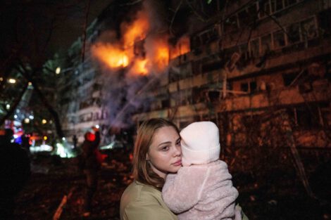 A woman holds her daughter in front of a residential building damaged in a Russian missile strike in Kyiv this week. (Evgeniy Maloletka/AP)