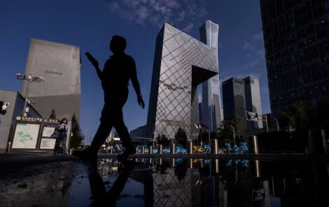 A man is reflected in a puddle as he walks past the CCTV building in Central Business District of Beijing, China August 13, 2025. REUTERS/Maxim Shemetov