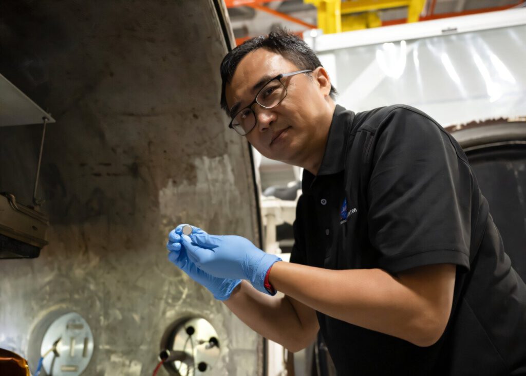 Yi Lin, SPEARS testing and research lead at NASA Langley, holds one of the small coin-cell batteries that had just undergone thermal vacuum testing. Credit: NASA/Ryan Hill